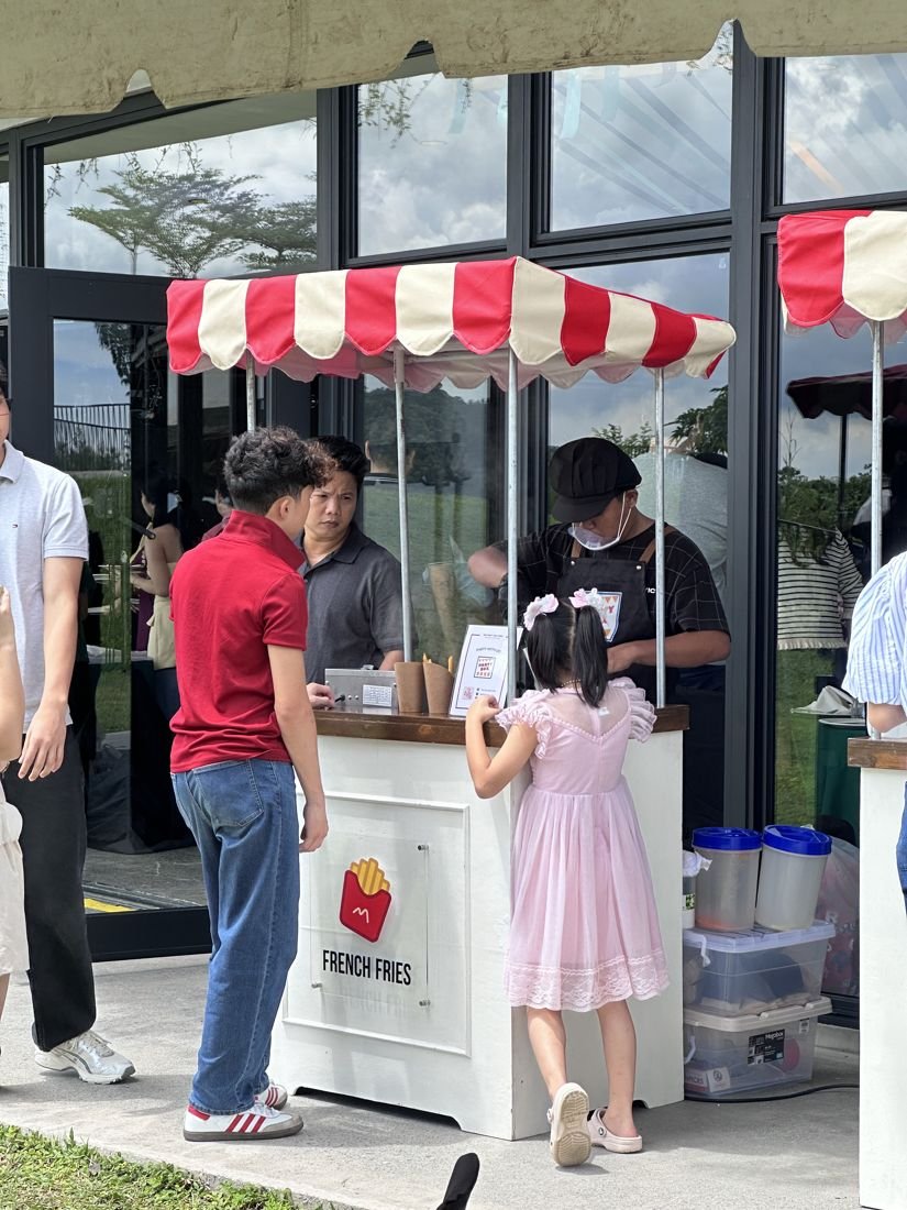 A girl in a pink dress ordering at the French fries cart