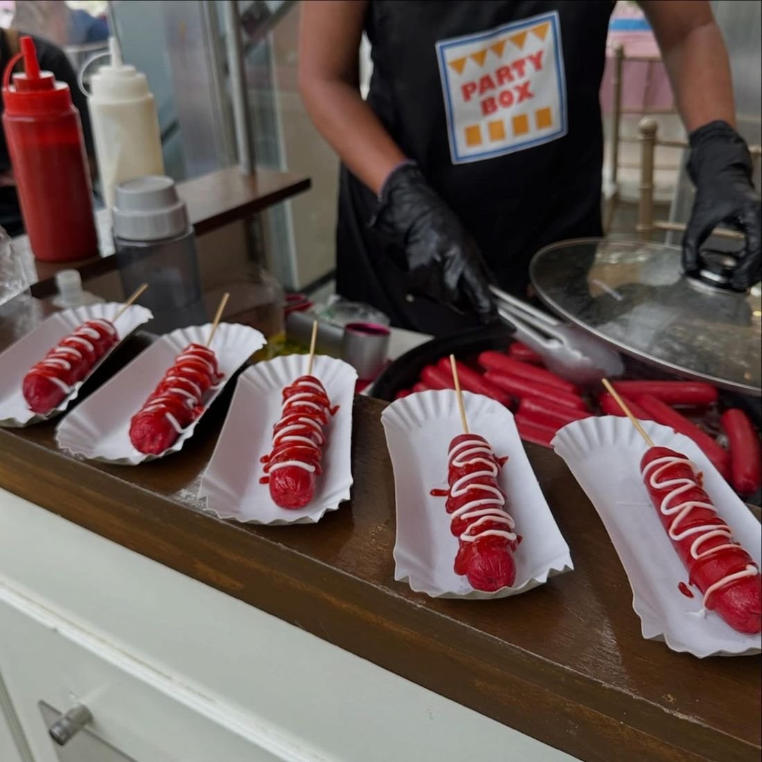 Skewered hotdogs with ketchup and mayo on paper trays